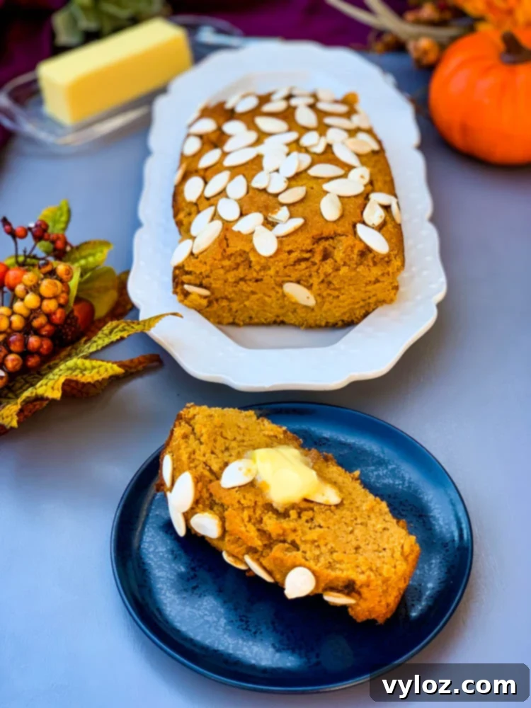Keto low carb pumpkin bread on a white plate with a slice on a blue plate, garnished for autumn