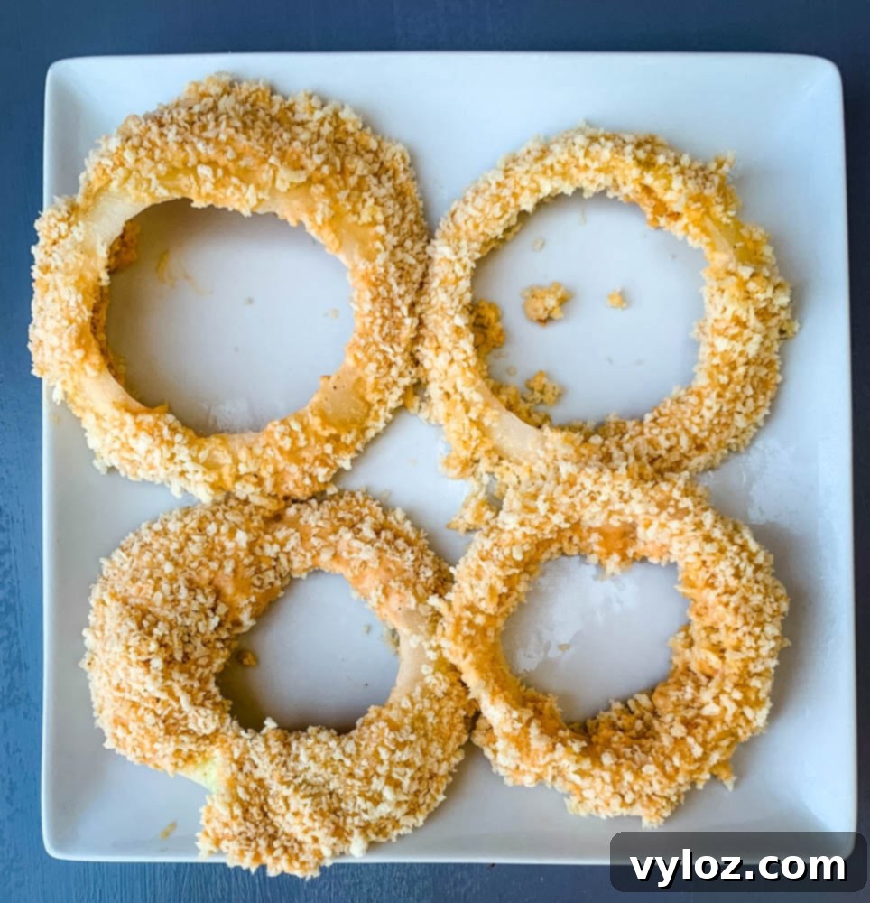 battered uncooked air fryer onion rings on a white plate