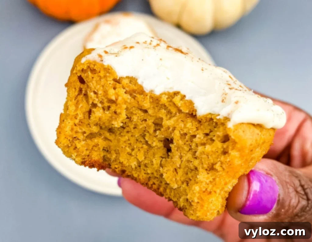 person holding half eaten keto pumpkin muffin with cream cheese
