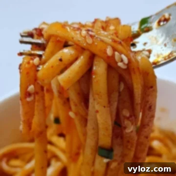 Fork holding mouth watering garlic chili oil noodles.