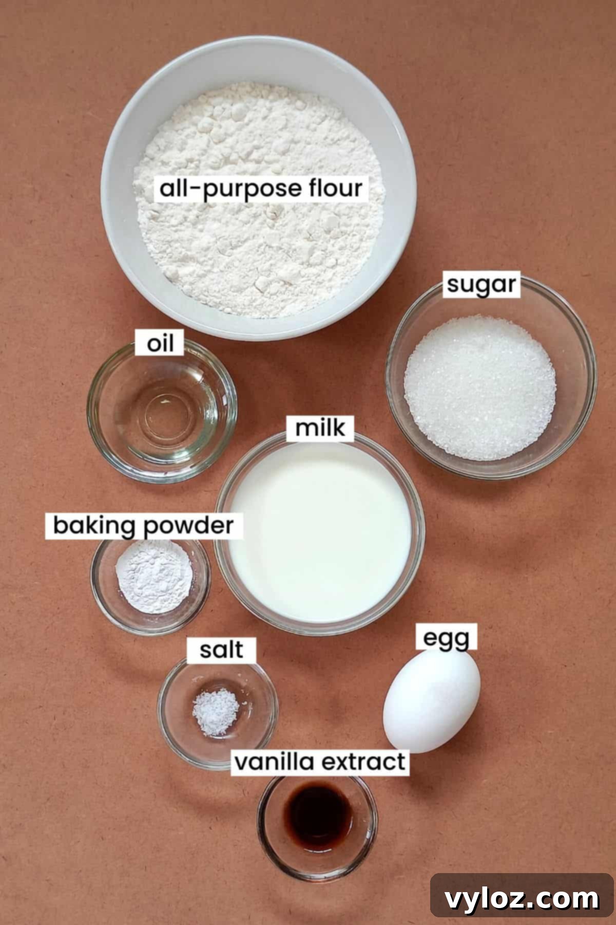 Image showing ingredients for making pancakes placed on an earthy background, including flour, milk, eggs, sugar, and oil.