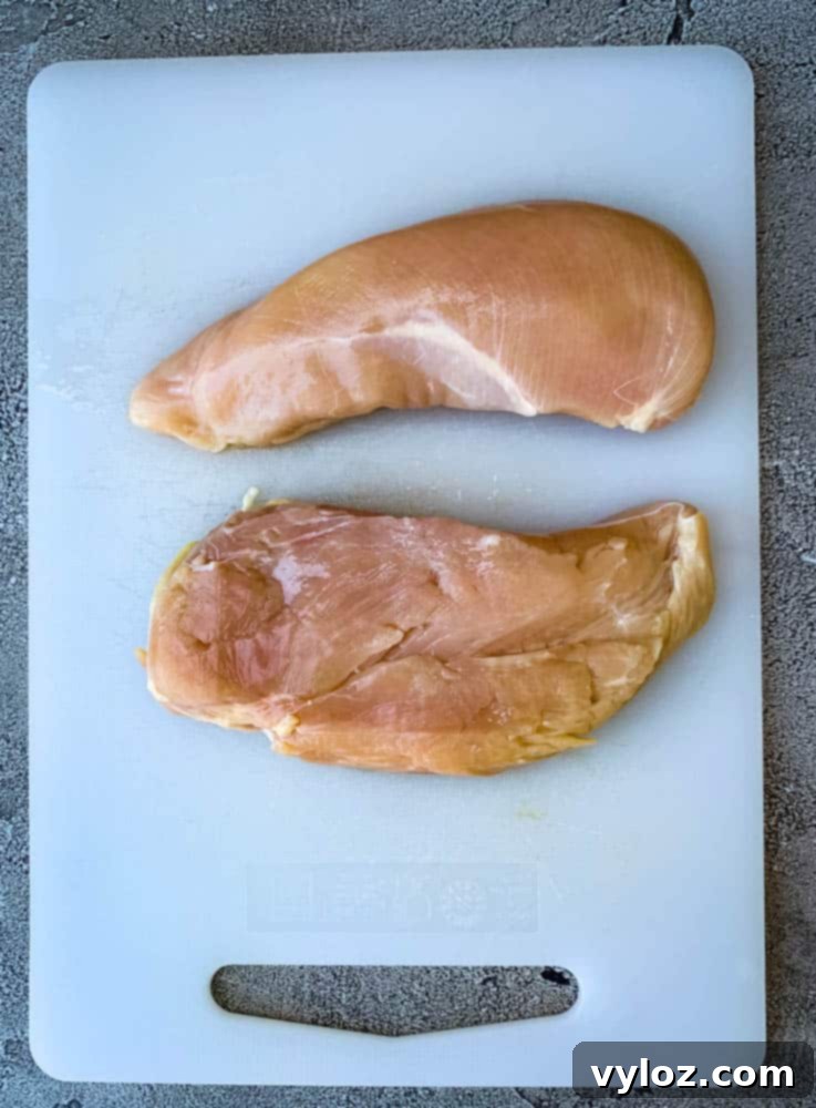 Raw chicken breasts on a wooden cutting board, ready for preparation