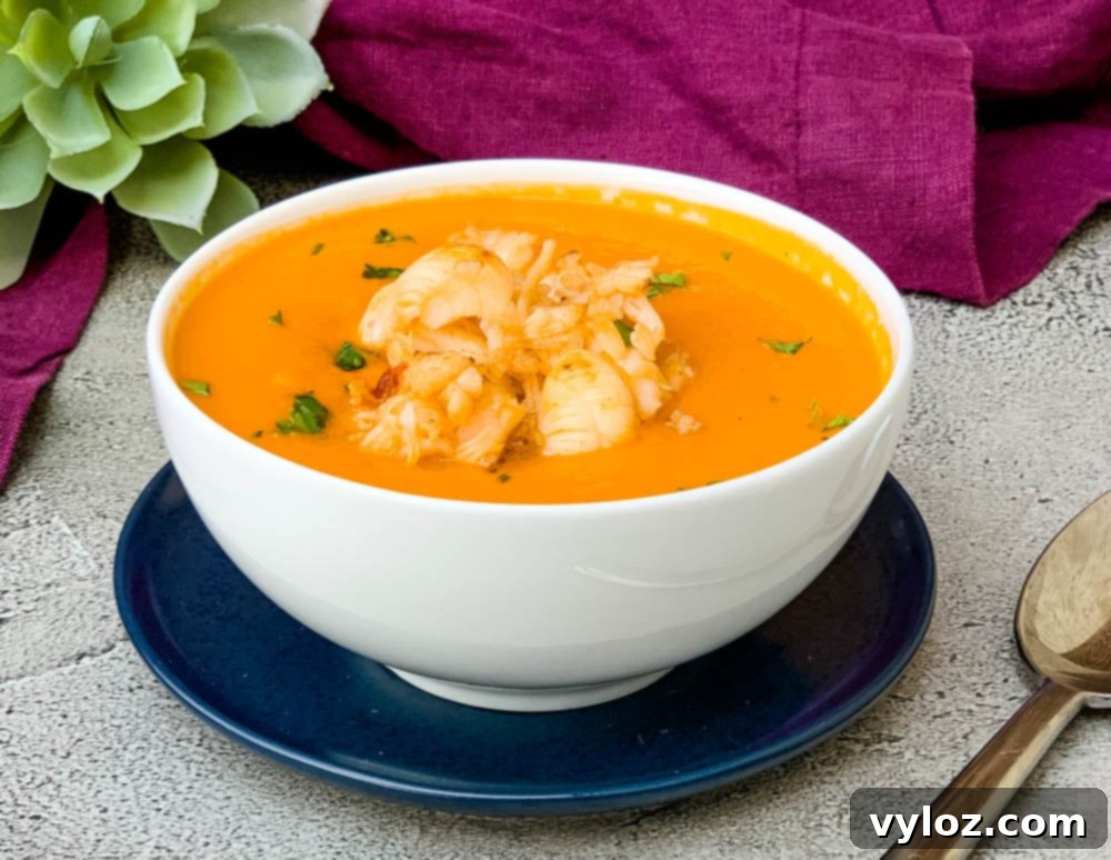 A beautifully presented bowl of creamy homemade lobster bisque soup, garnished with fresh herbs, resting on a rustic wooden table with a purple towel. Perfect for a cozy night in.