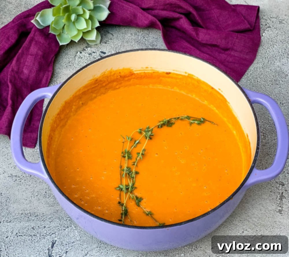 A stunning shot of creamy homemade lobster bisque simmering gently in a vibrant purple Dutch oven, its rich texture and enticing color promising a gourmet experience. The ideal vessel for cooking and serving.