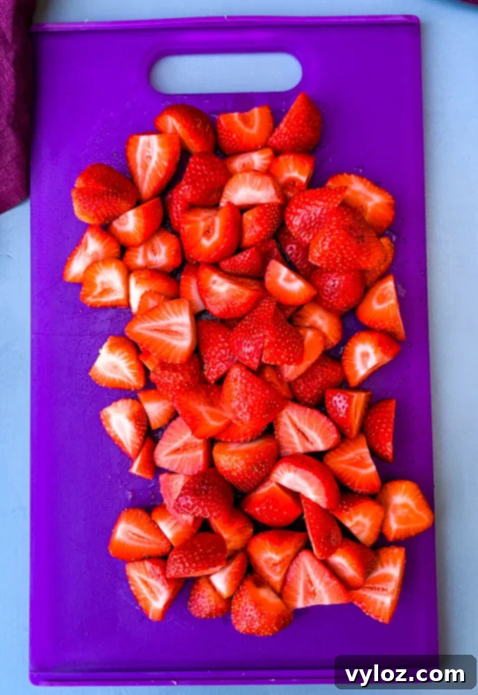 Freshly sliced strawberries on a cutting board, ready to be added to Jungle Juice