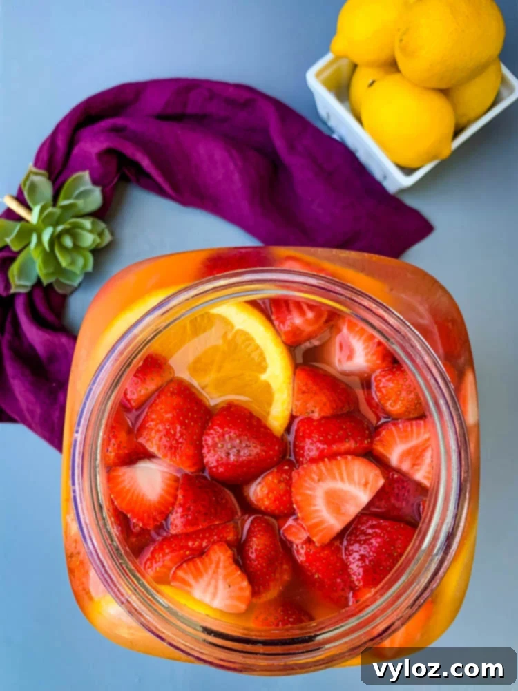 Jungle Juice cocktail recipe in a 2-gallon glass container with an assortment of fresh fruit, close-up