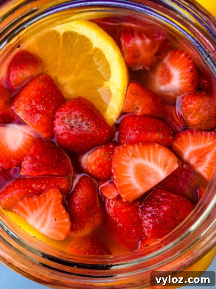 Refreshing Jungle Juice cocktail recipe in a 2-gallon glass container, adorned with fresh fruit slices