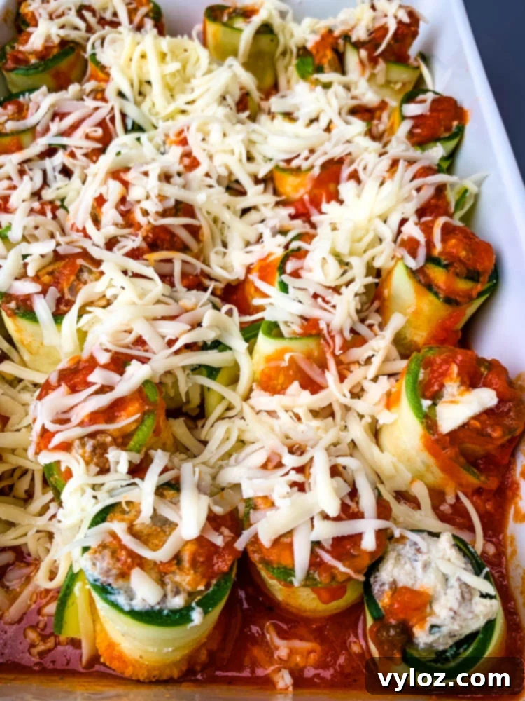 Quick Zucchini Lasagna Pinwheels 11 Closer view of baked zucchini lasagna roll ups in a white baking pan, showing the rich marinara and melted cheese.