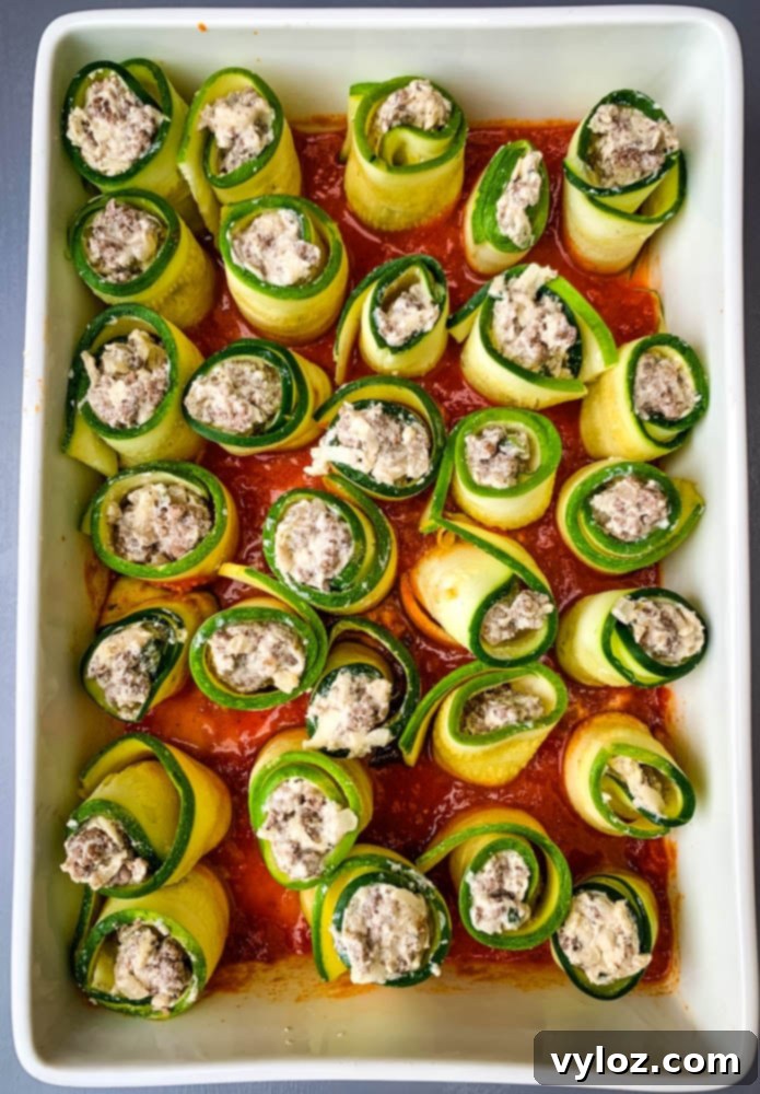 Quick Zucchini Lasagna Pinwheels 8 Close-up of neatly arranged raw zucchini lasagna rolls in a white baking dish, ready for sauce and cheese.