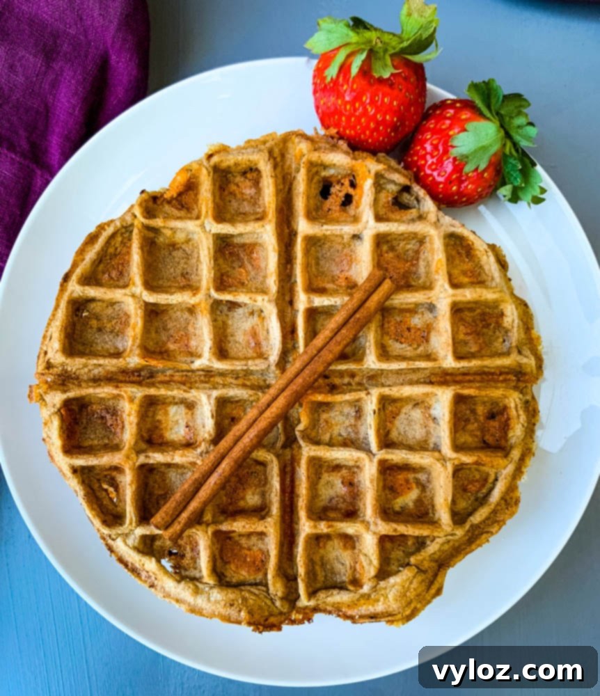 Two keto low carb cinnamon roll chaffles served on a pristine white plate, showcasing their golden-brown finish.