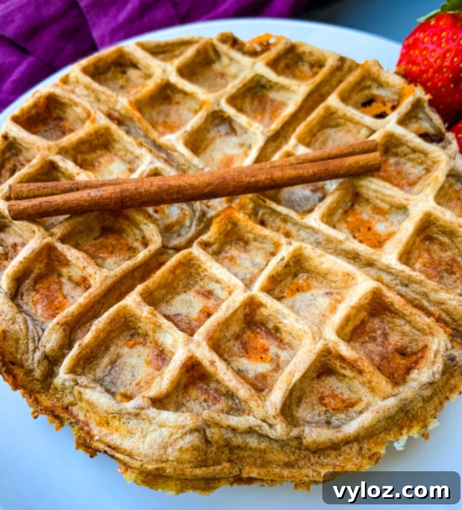 A single keto low carb cinnamon roll chaffle on a white plate, showcasing its fluffy texture.