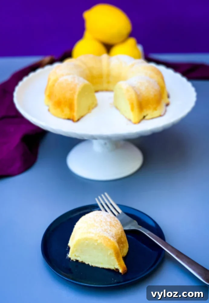 air fryer lemon cake on a white cake stand with fresh lemons