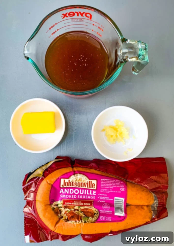 Beef broth, butter, minced garlic, and sliced andouille sausage, key ingredients for Instant Pot Cabbage