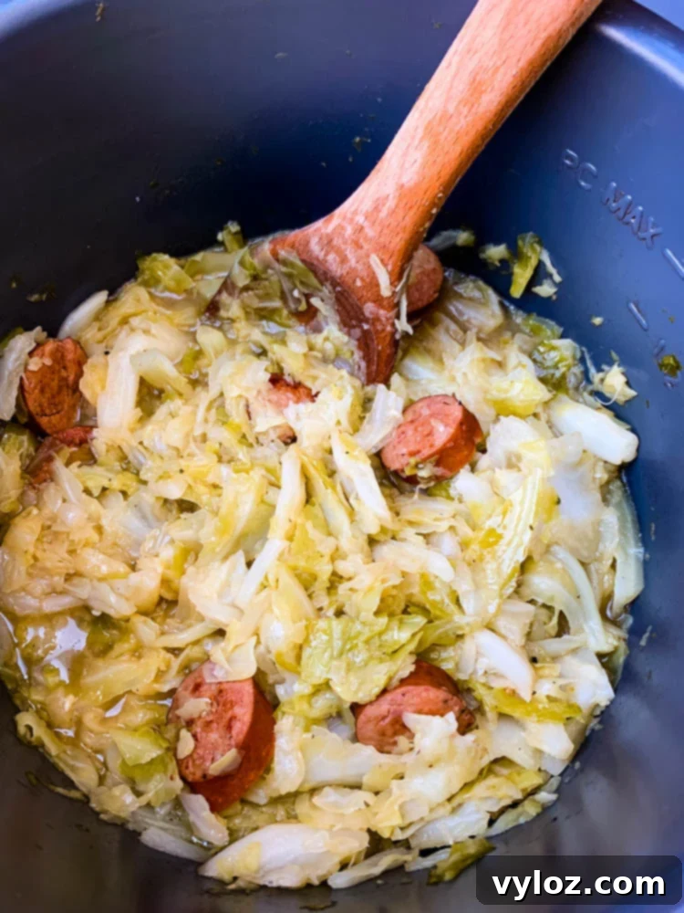 Instant Pot Cabbage and Sausage with a spoon, ready to be served from the Instant Pot