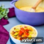 Savory Keto Cheeseburger Bliss 12 keto low carb cheeseburger soup in a white bowl with pickles, tomatoes, and bacon