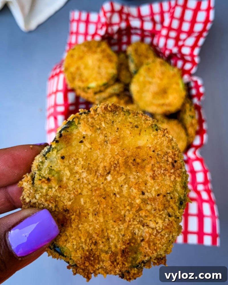 person holding air fryer zucchini chip