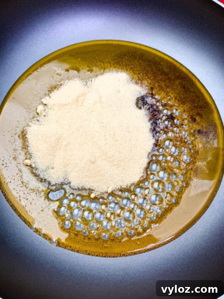 A close-up view of honey, ground cloves, and brown sugar simmering gently in a pan, as they blend to form the aromatic glaze for an air fryer honey glazed ham.