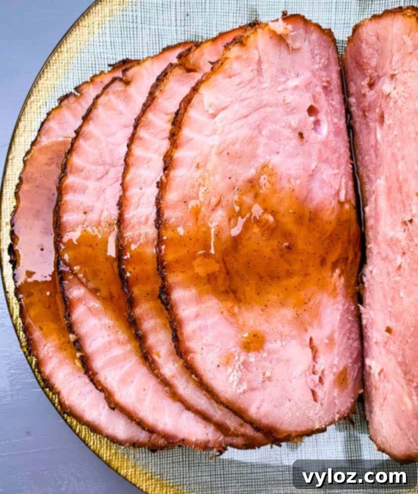 A magnificent air fryer honey glazed ham is served on an elegant green and gold plate, highlighting its rich, caramelized crust and inviting presentation.