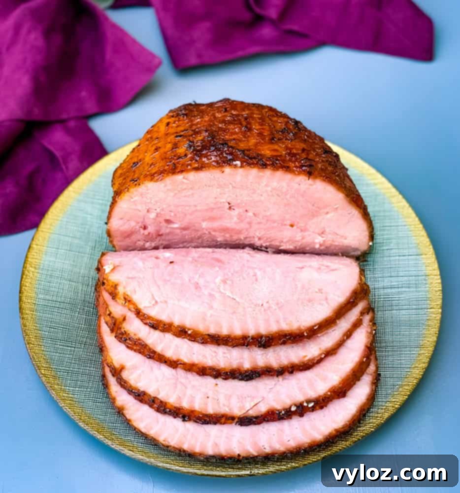 A succulent air fryer honey glazed ham, with its rich, golden crust, is elegantly displayed on a green and gold plate, promising a delicious and festive meal.