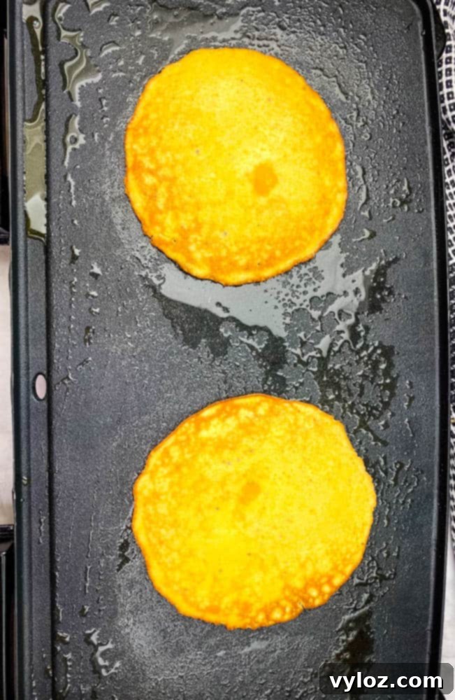 keto low carb pancakes cooking on a griddle