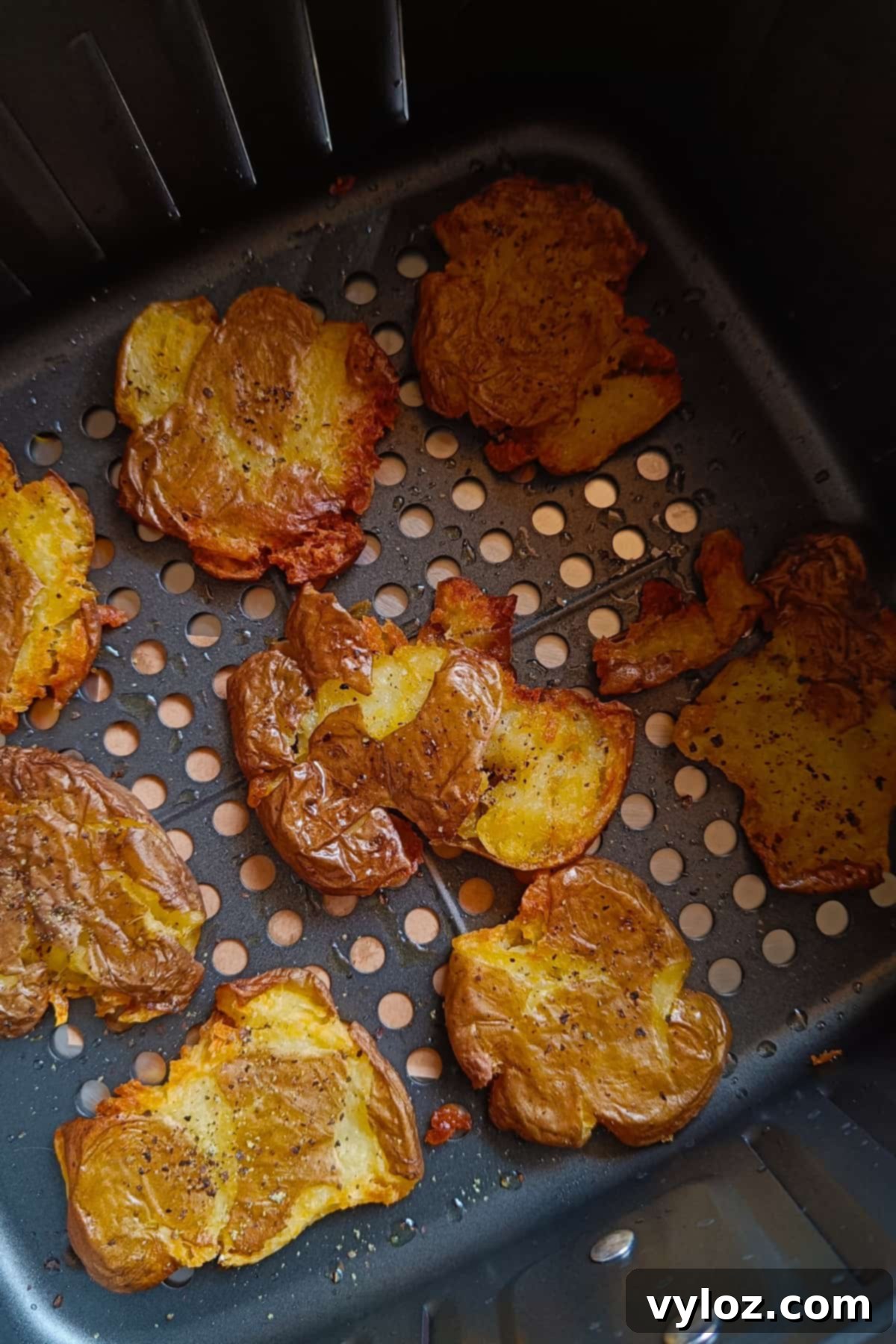 Golden crispy smashed potatoes in the air fryer basket.