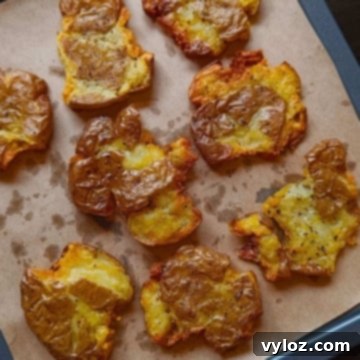 golden brown, crispy smashed potatoes arranged on a tray lined with parchment paper.