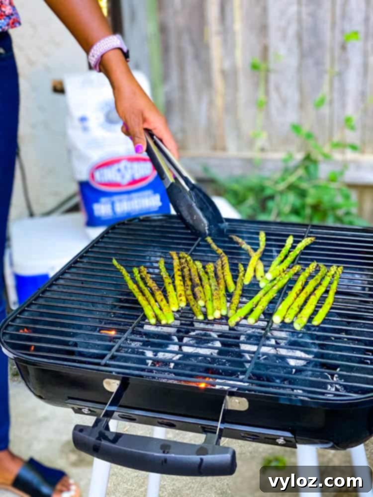 person grilling asparagus on a charcoal grill