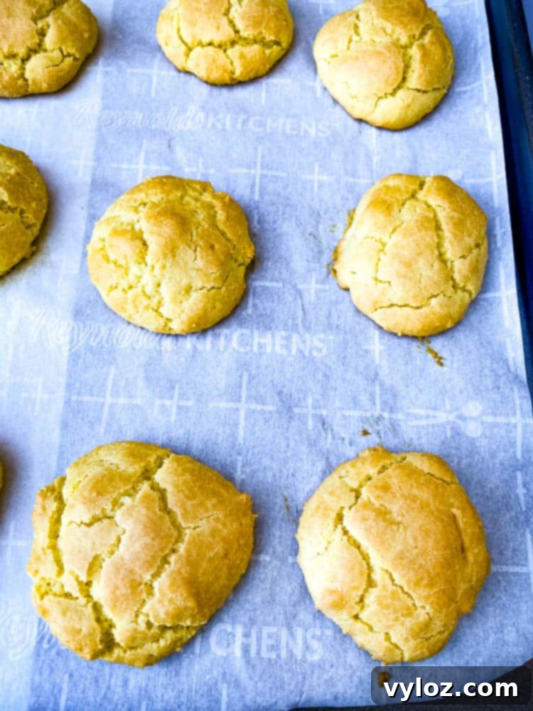 Close-up of freshly baked golden keto low carb biscuits with a tender crumb, resting on parchment paper.