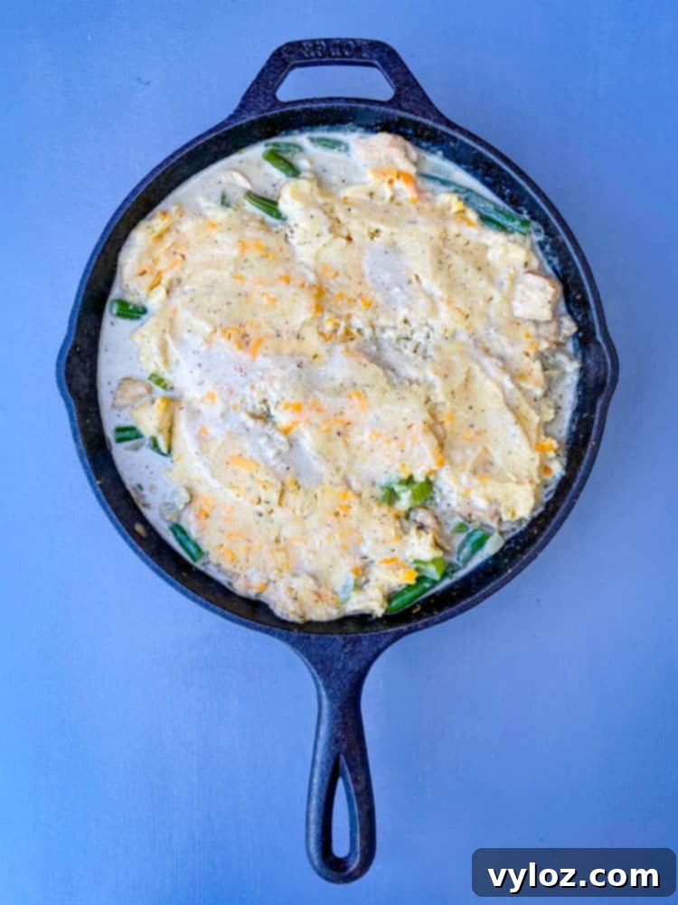 Uncooked keto low carb chicken pot pie in a cast iron skillet, with the almond flour crust laid over the creamy filling