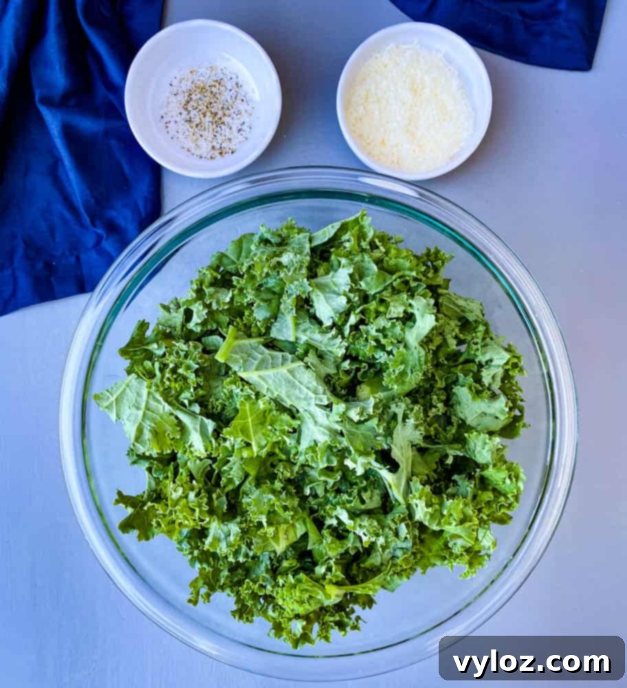 Freshly washed raw kale in a clear glass bowl, ready for air frying into healthy chips