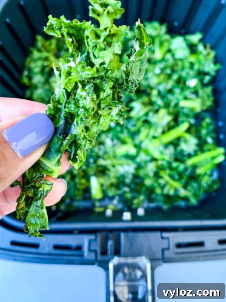 Hand holding a handful of freshly made crispy air fryer kale chips