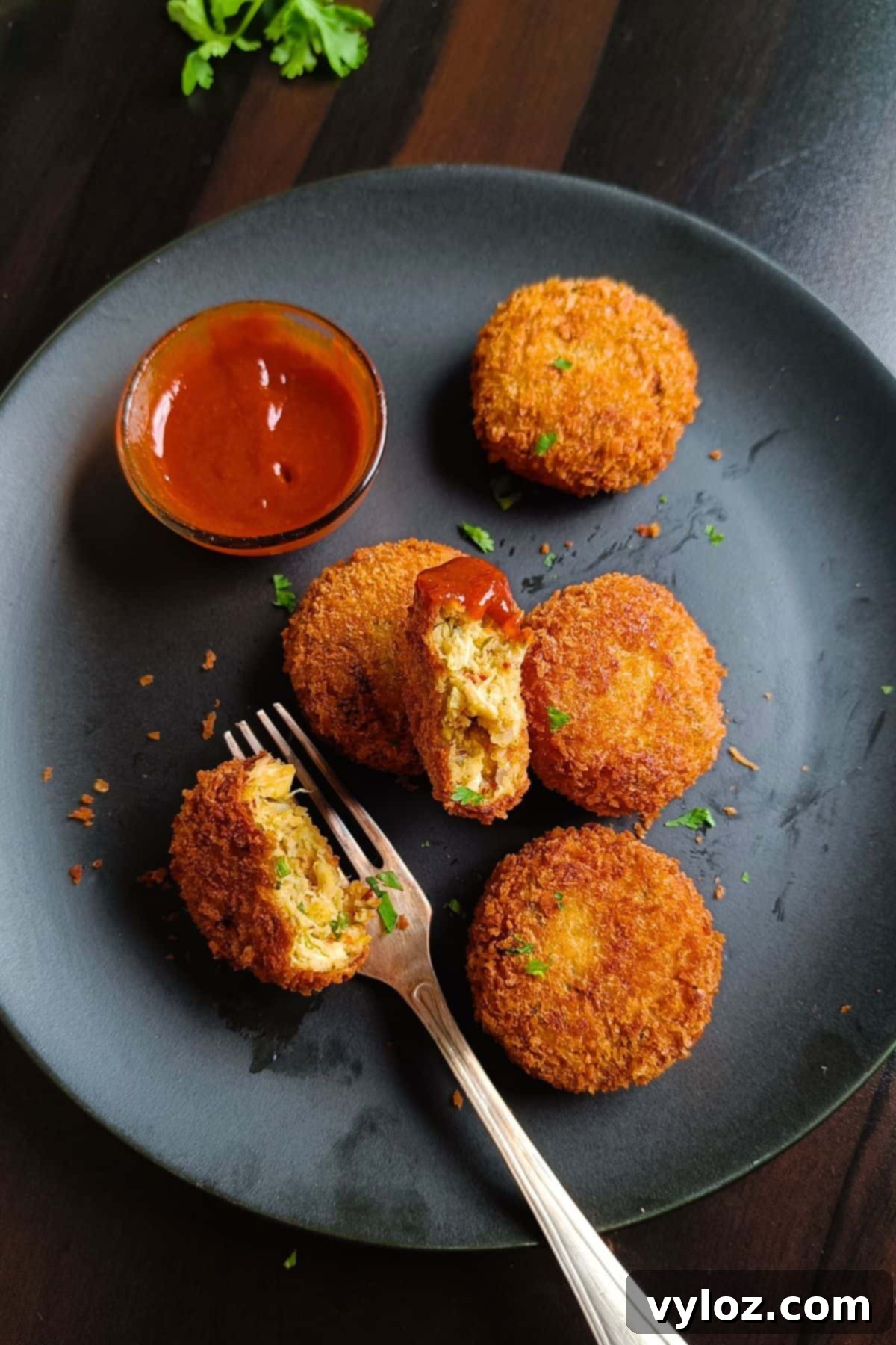 Image showing chicken cutlets served on a black platter, garnished with fresh herbs.