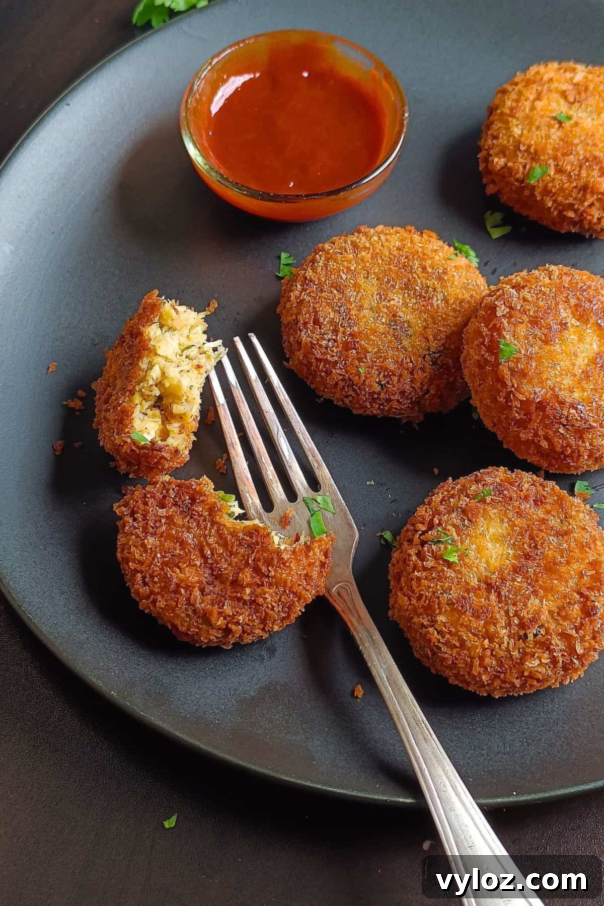A close-up image showing perfectly cooked, golden-brown chicken potato cutlets served on an elegant black platter.