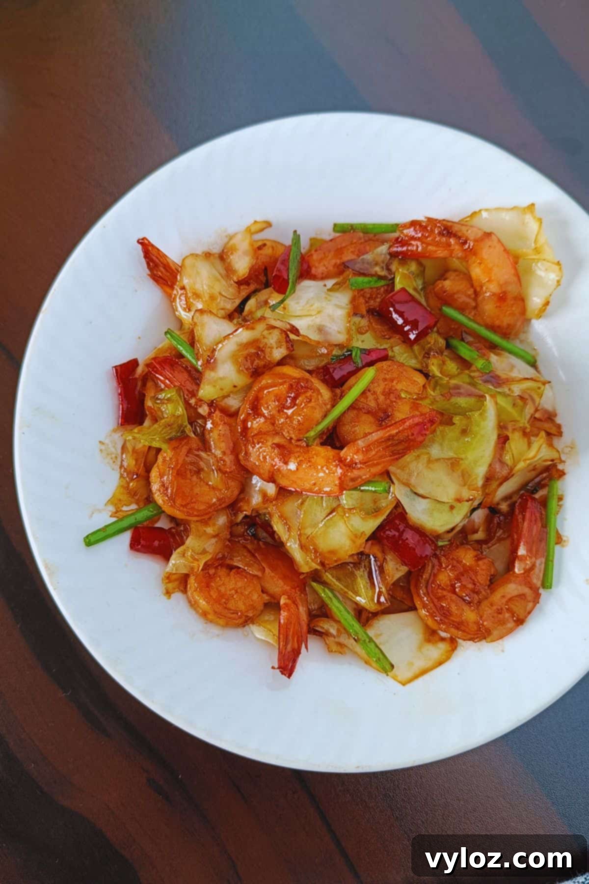 Vibrant stir-fried shrimp and cabbage served on a white plate, ready to eat.