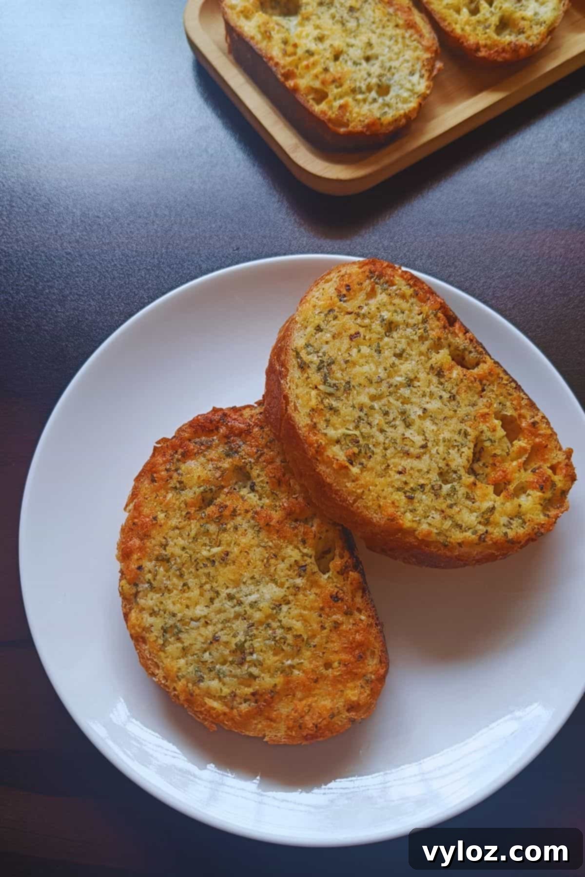 Freshly air-fried garlic bread slices served on a white plate, ready to be enjoyed.