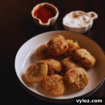 Air fryer chicken nuggets served in a white platter with a bowl of dipping sauce.