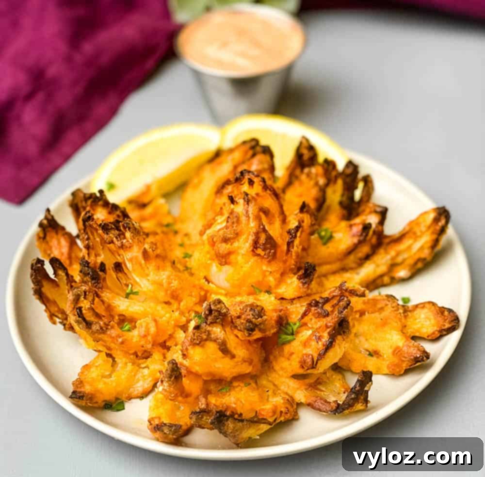 Restaurant-Style Air Fryer Blooming Onion 2 Crispy Air Fryer Blooming Onion served on a plate with fresh lemon slices, ready to be enjoyed.