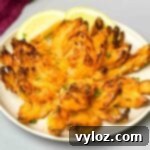 Restaurant-Style Air Fryer Blooming Onion 12 air fryer blooming onion on a plate with sliced lemons