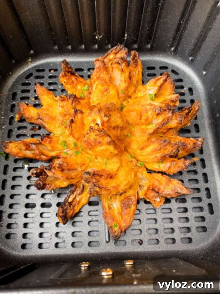 Restaurant-Style Air Fryer Blooming Onion 7 A golden-brown, crispy Air Fryer Blooming Onion cooking inside an air fryer, nearly ready.