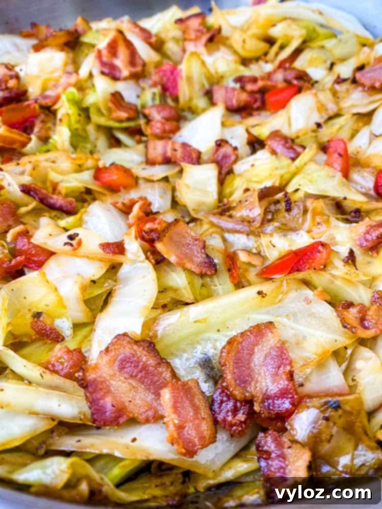 Another view of Southern fried cabbage with bacon in a stainless steel pan, highlighting its vibrant colors and savory appeal.