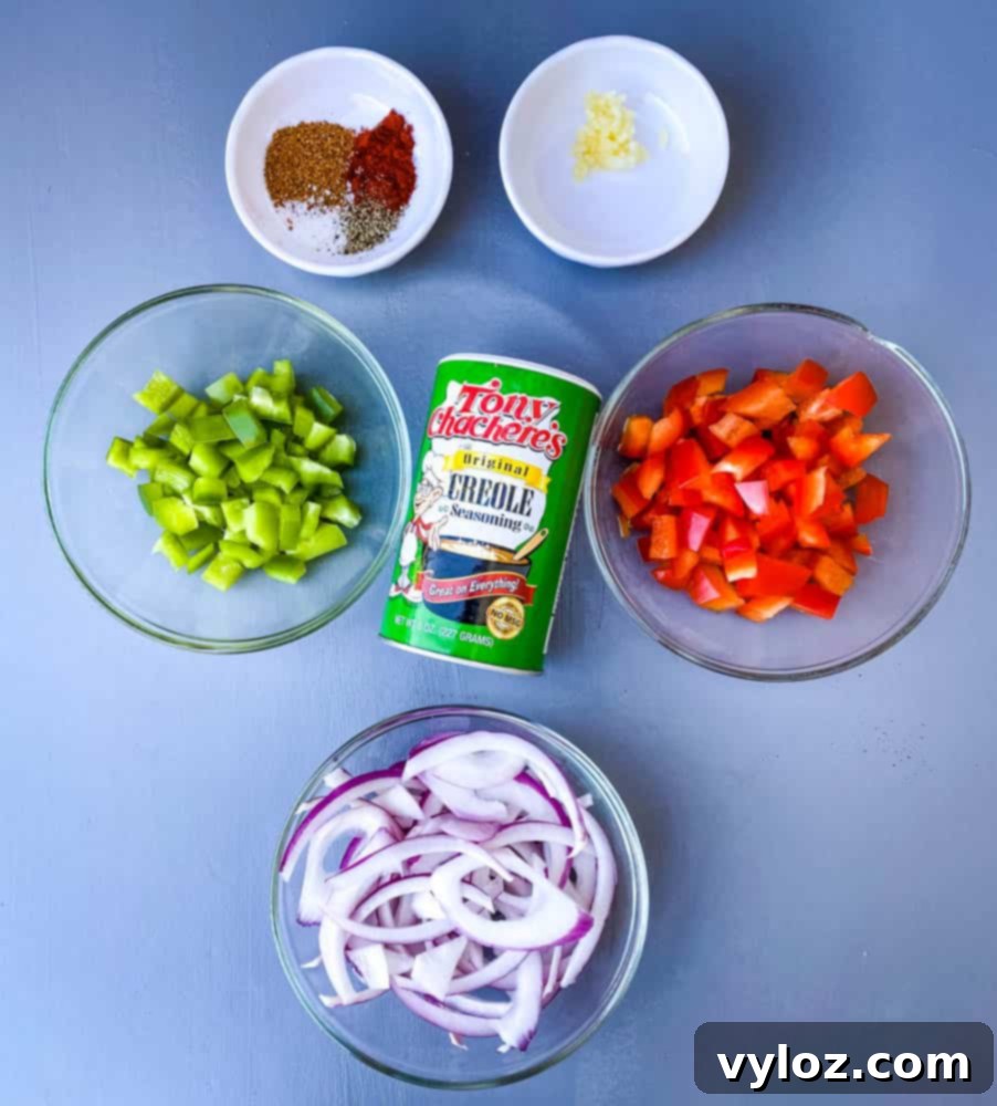 A vibrant array of chopped green bell peppers, red bell peppers, sliced onions, Creole seasoning, and minced garlic laid out, ready for southern fried cabbage preparation.
