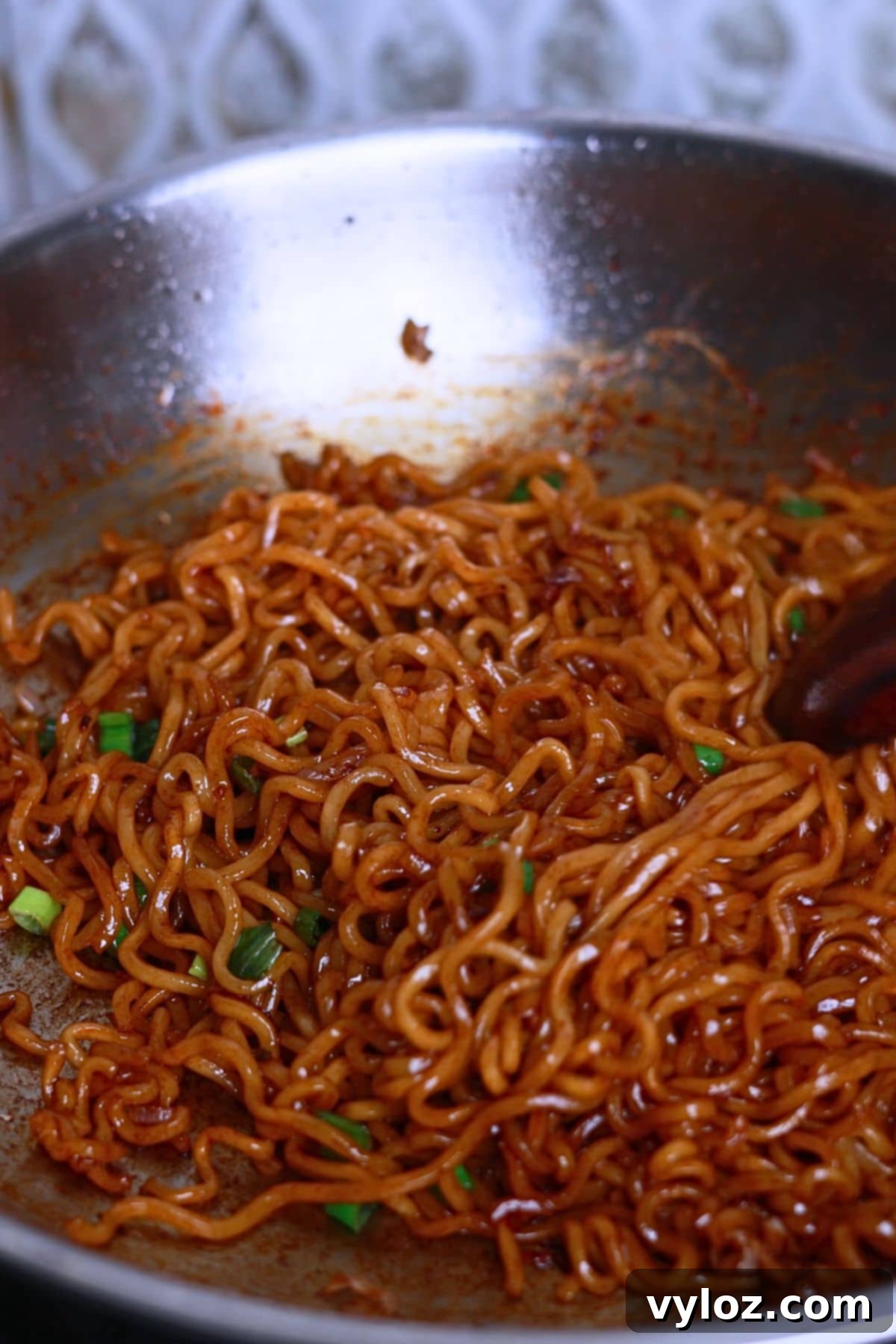 Image showing vibrant looking noodles in a pan, garnished with fresh greens.