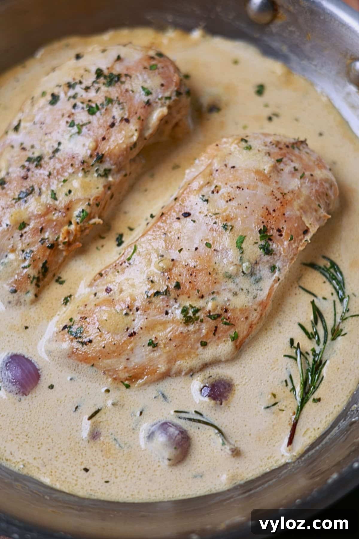 Perfectly cooked chicken breast adorned with creamy, silky garlic sauce and fresh herbs, ready to be served.
