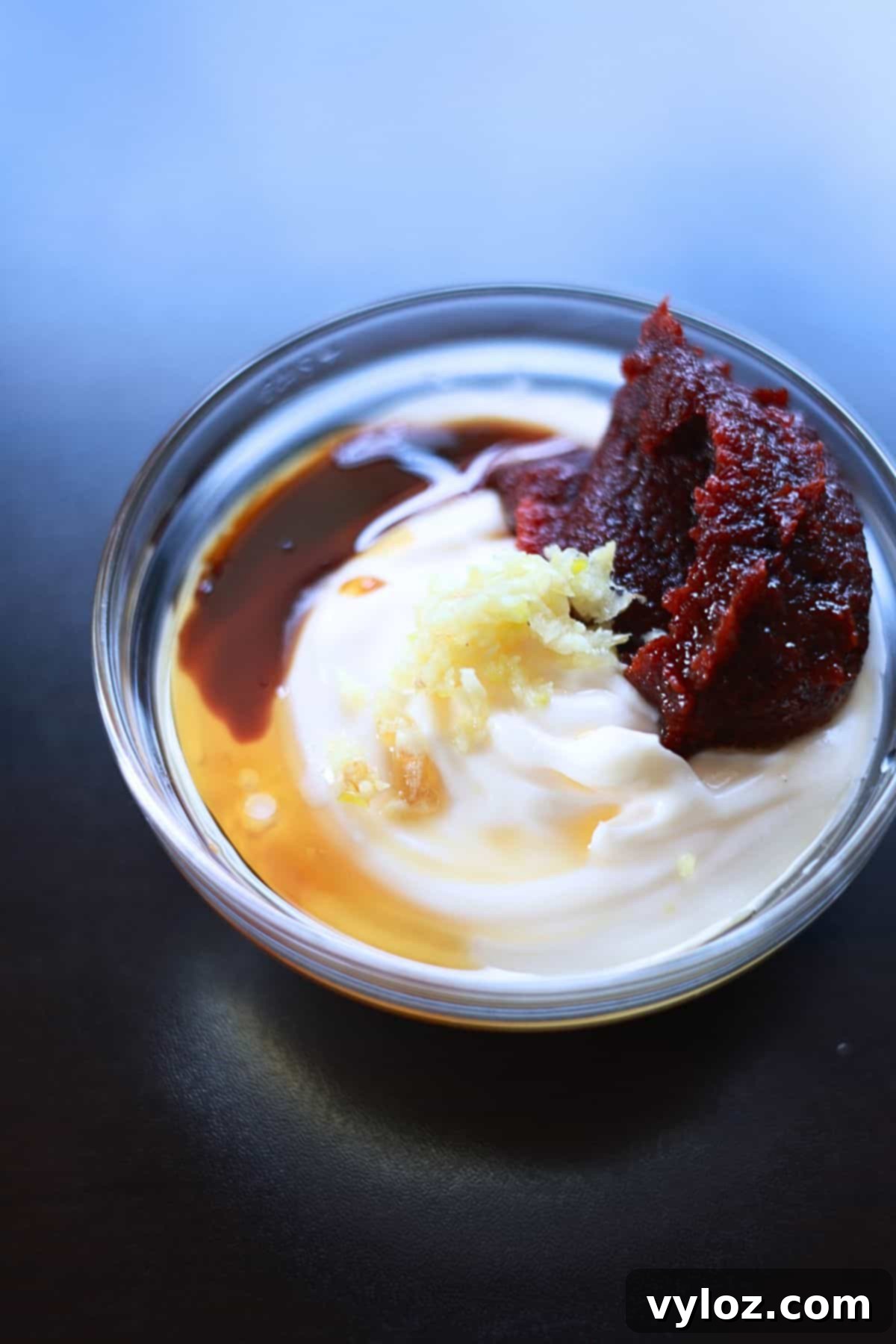 Deliciously Easy Korean Gochujang Aioli 4 Image showing mixing gochujang, mayo, and other ingredients together in a bowl with a spoon.