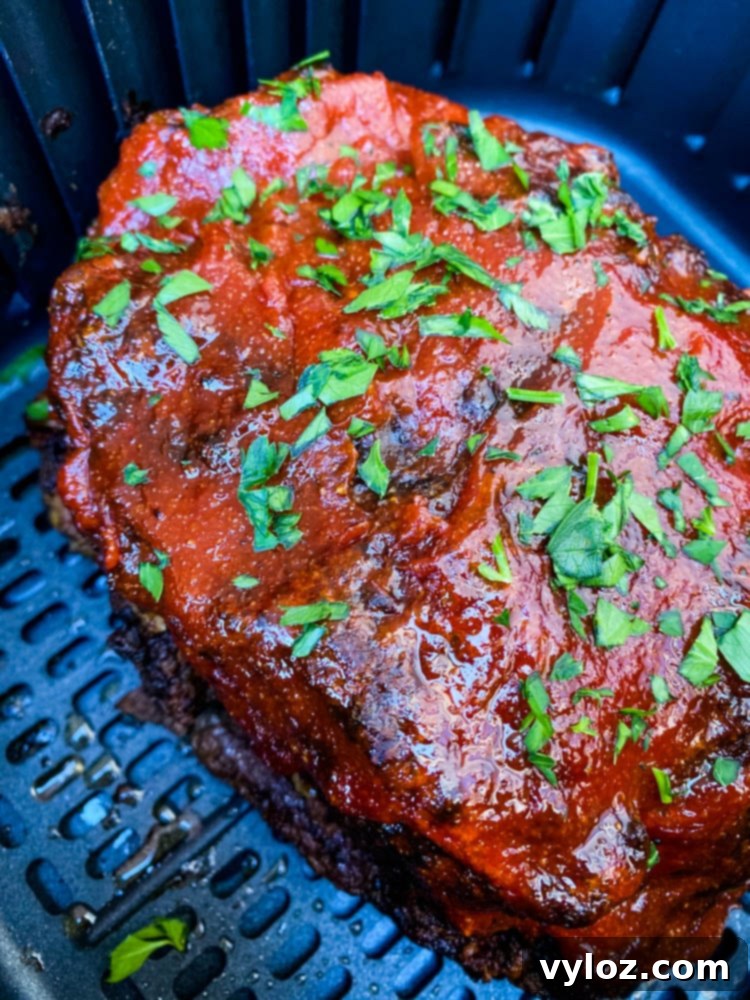 Meatloaf cooking in an air fryer basket, showing a golden-brown crust.