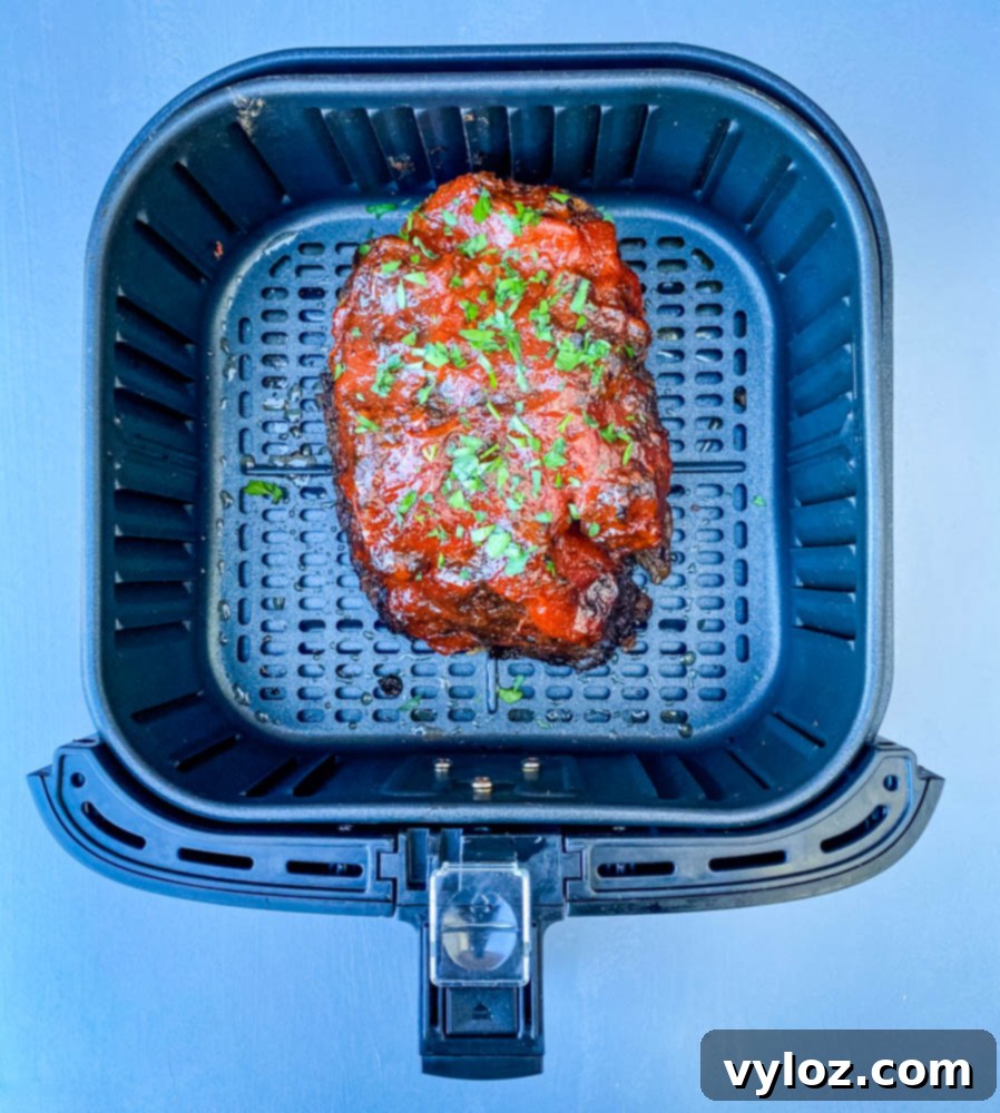 Sliced meatloaf in an air fryer, showcasing its juicy interior and glazed top.