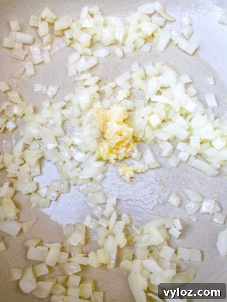 Sautéing chopped onions and minced garlic in a Dutch Oven, creating a fragrant base for a delicious keto low carb marinara sauce.