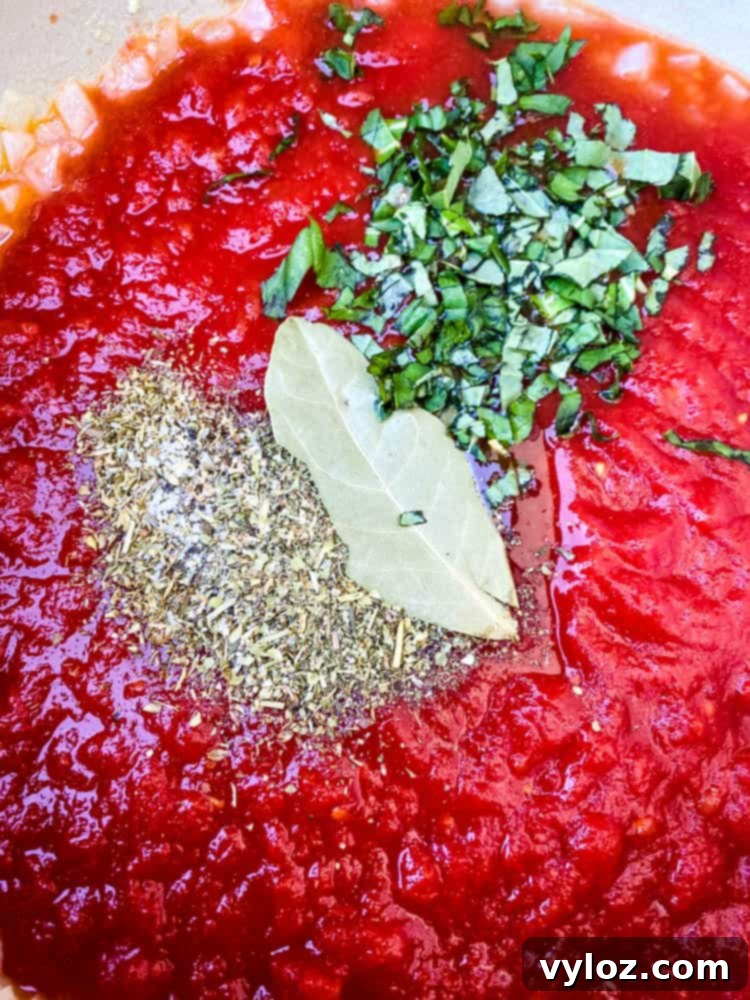 Crushed tomatoes and a blend of aromatic spices simmering in a Dutch oven for a savory keto low carb marinara sauce.