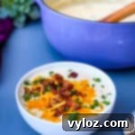 keto low carb cauliflower soup in a white bowl with shredded cheese and bacon