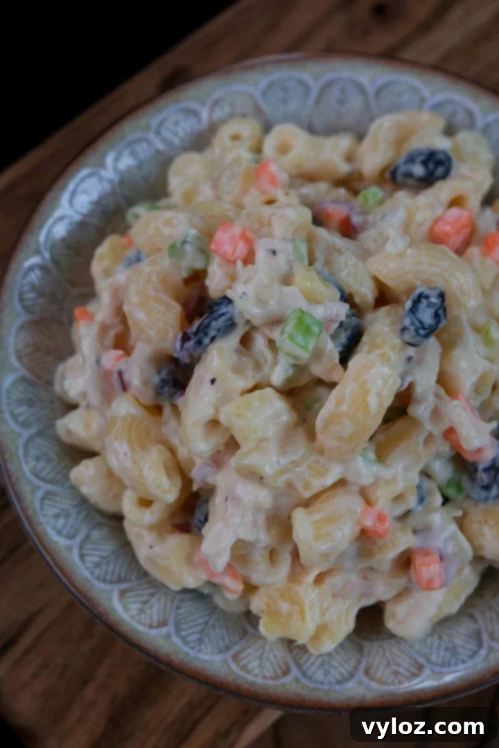 A vibrant bowl of Filipino chicken macaroni salad, showcasing its creamy dressing and colorful mix-ins like chicken, pineapple, and vegetables.